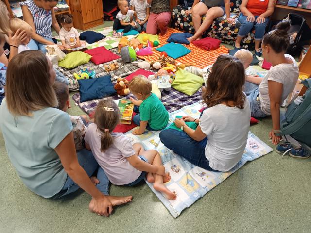 Mütter und Kinder sitzen auf Decken am Boden